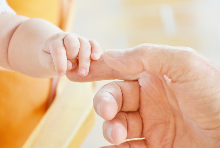 baby close up holding parents hand